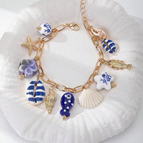 Bracelet artisanal esprit bord de mer, chaîne dorée et breloques étoile de mer, coquillage, poisson, fleur et champignon – été