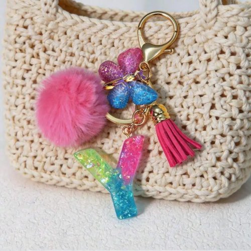 Llavero letra de resina con glitter, pompón rosa y dije de mariposa