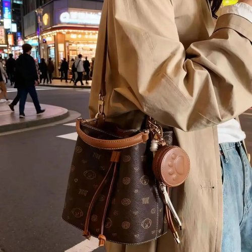 Bolso tipo bucket mini marrón oscuro con estampado de mascotas por toda la superficie y remates en piel a contraste; convertible en mochila o bandolera, complemento adorable
